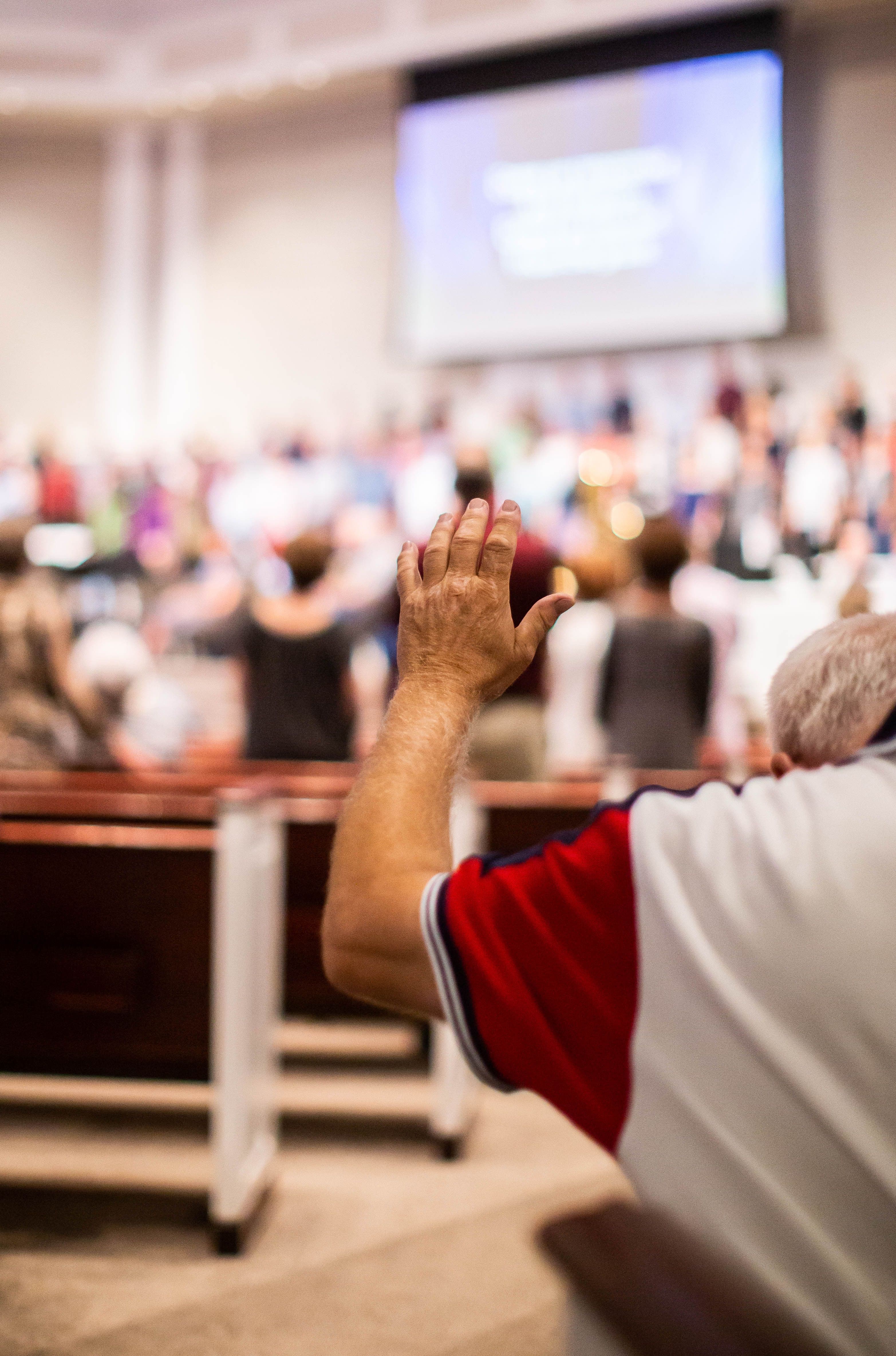 Representational stock photo of a worshipper raising a hand in church